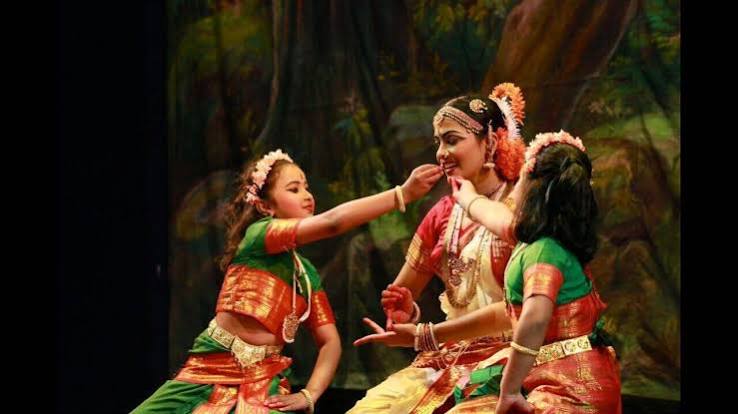 Sita with two young dancers in a forest scene